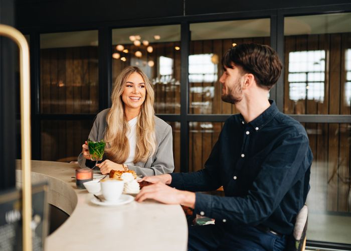 Man en vrouw aan de bar bij Gastrobar de Timmerfabriek. Ze eten appeltaart en brownie met koffie en een verse muntthee