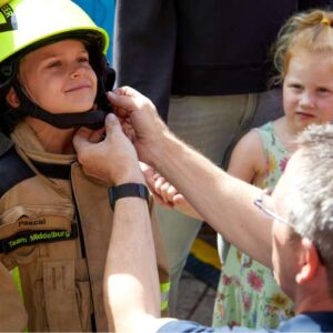 Jongetje wordt in een te groot brandweekpak geholpen tijdens Rescue Zeeland in Vlissingen